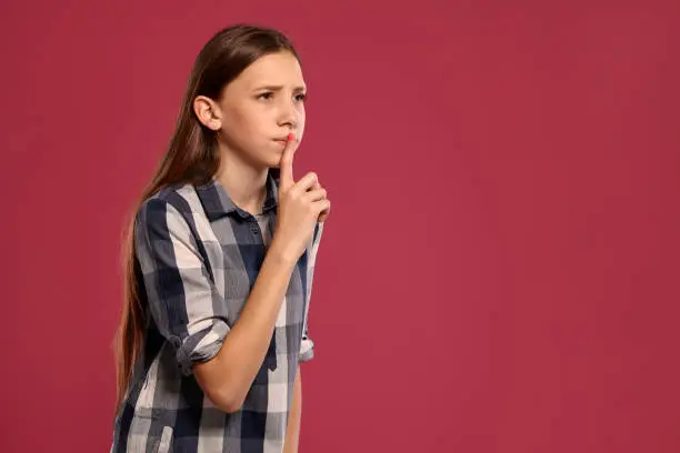Photo of Beautiful teenage girl in a casual checkered shirt is posing against a pink studio background