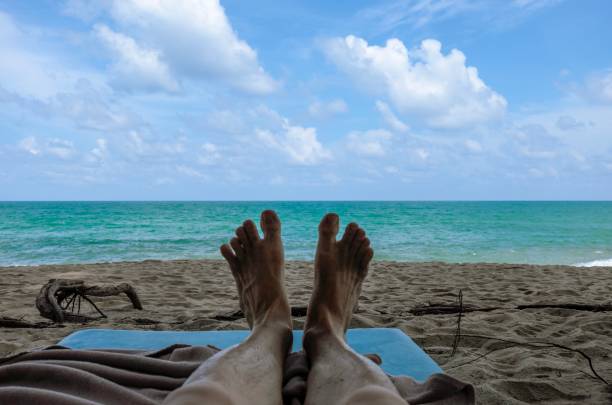 istock A man is lying down on a shaded beach with barefoot 1166826930