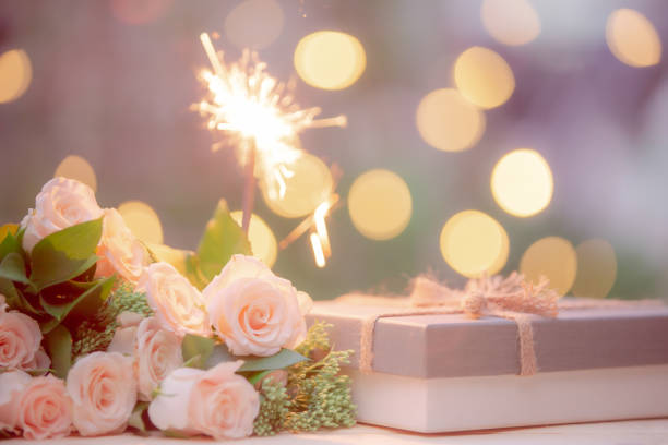 Rose flower, gift box, sparkler, on wooden table with bokeh background