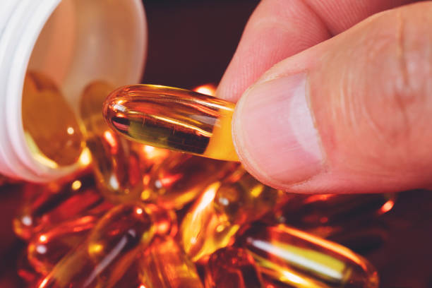 istock Hand holding a Fish oil capsule with blurred background 1166828260