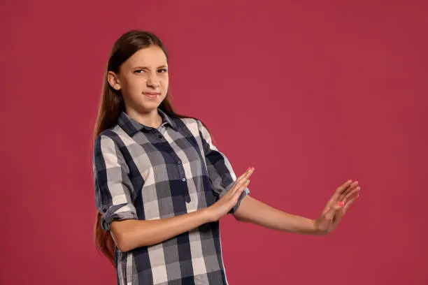 Photo of Beautiful teenage girl in a casual checkered shirt is posing against a pink studio background