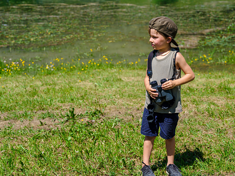 Child looking with binoculars at the wild nature in a mountain park