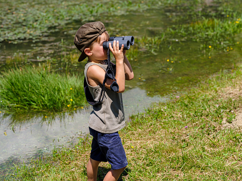 Child looking with binoculars at the wild nature in a mountain park