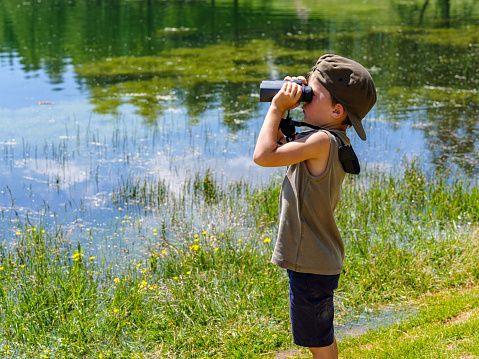 Child looking with binoculars at the wild nature in a mountain park