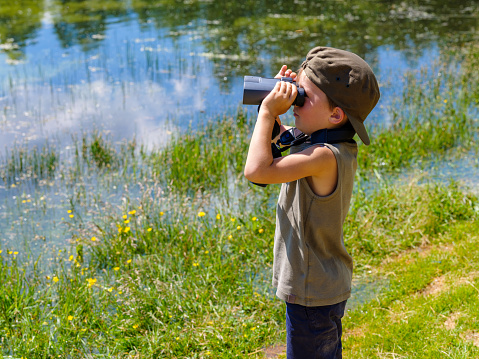 Child looking with binoculars at the wild nature in a mountain park