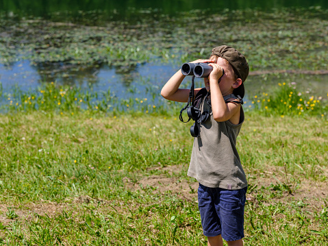 Child looking with binoculars at the wild nature in a mountain park