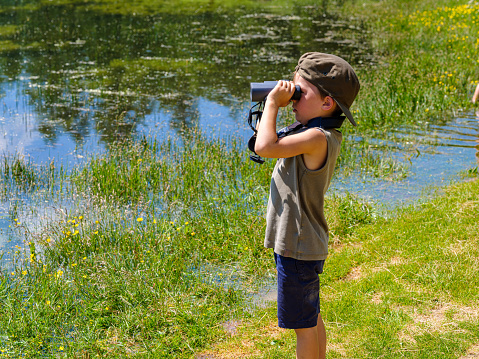 Child looking with binoculars at the wild nature in a mountain park