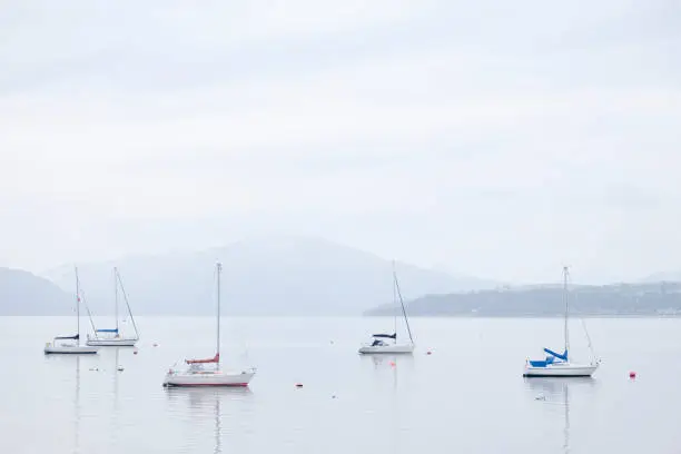 Boats resting in calm tranquil water surround by mountains in Scottish landscape uk