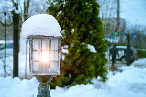 Old street lamp under the snow. On New Year's Eve, on the fir tree