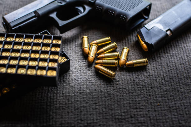 balles et pistolet sur le bureau de velours noir - handgun gun blue black photos et images de collection