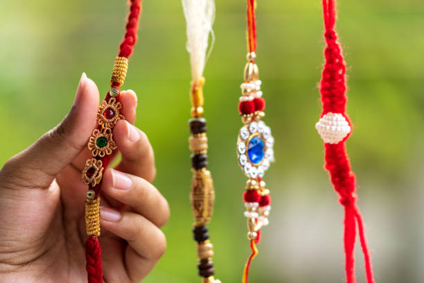 Handmade Beautiful Rakhi Selective focus of a beautiful hand crafted rakhi held by a women.Beautiful green blurred background for copy space. rakhi stock pictures, royalty-free photos & images
