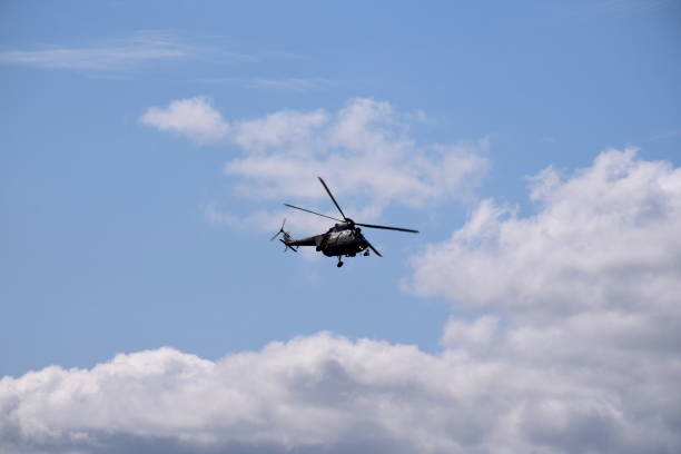 istock A single massive military helicopter painted in dark navy green flying dyamically with its rotor blades spinning quickly across a cloudy summer sky at a high altitude in Poland 1166850698