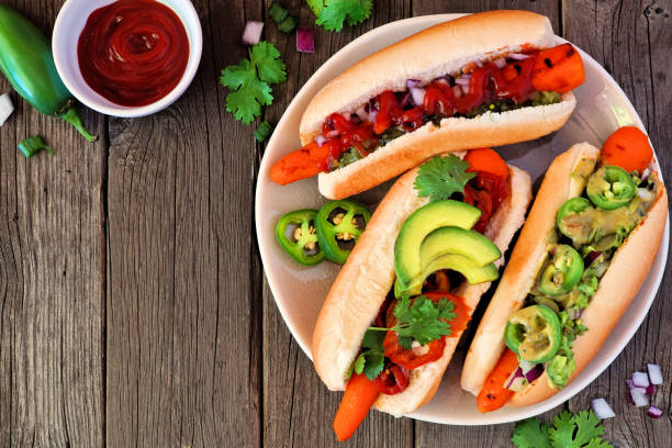 istock Carrot hot dogs with assorted toppings, top view table scene with a wood background 1166850703