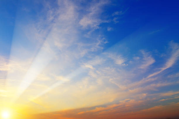 Cloudy sky and bright sun rise over the horizon.