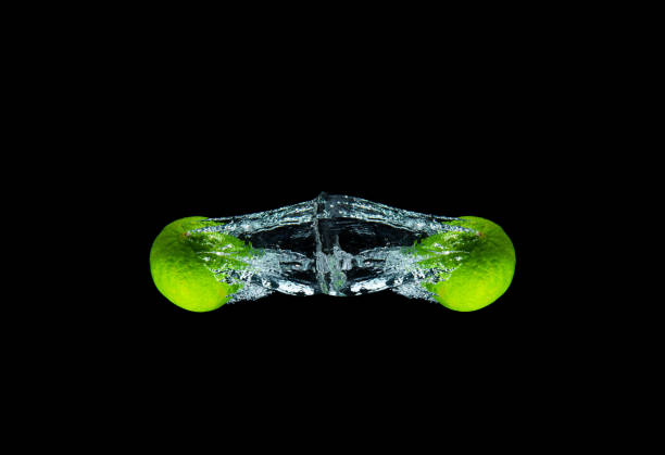 Fresh and delicious lime isolated against dark, black background. Lime dropping in water and creating a splash.