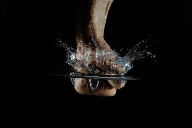 istock A hand hits the water while making a splash isolated on a dark background. 1166853227