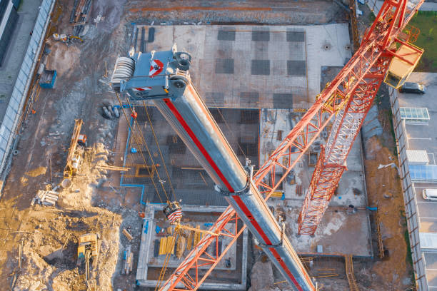 Aerial view, crane truck at the construction site works the installation of the boom of a tower crane, against the background of the foundation of the building under construction. Aerial view, crane truck at the construction site works the installation of the boom of a tower crane, against the background of the foundation of the building under construction jib stock pictures, royalty-free photos & images