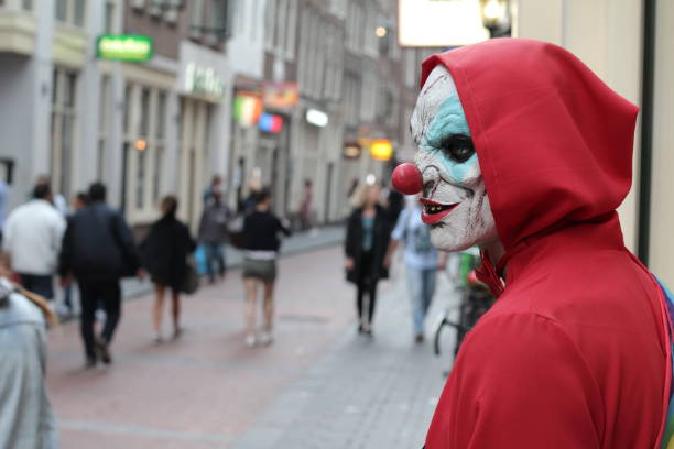 Spooky clown looking for his victim in crowded place.