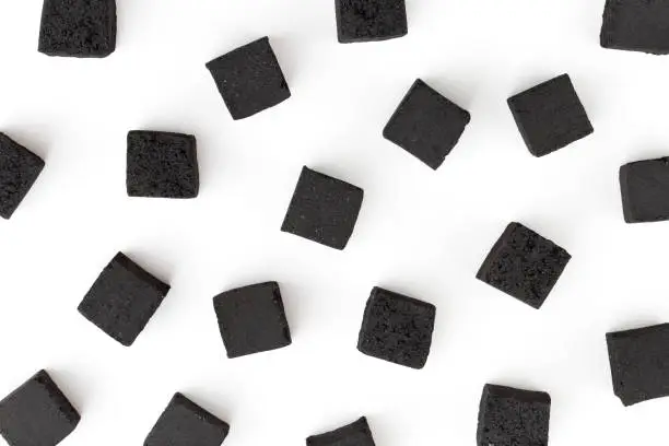 Photo of Coconut charcoal on a white background. Coconut coal cubes for hookah close-up.