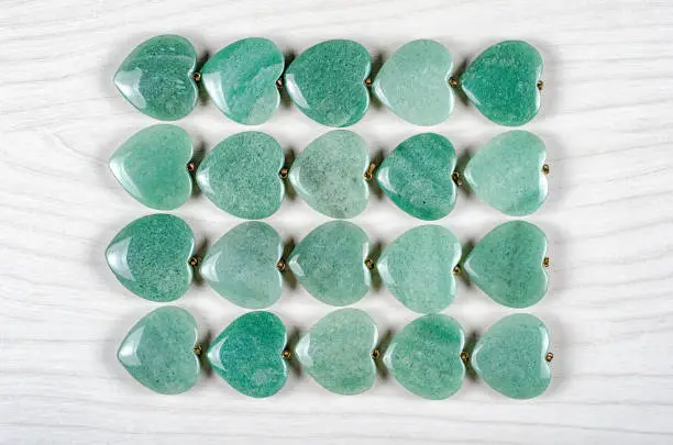 Twenty green aventurine heart-shaped stones are stowed four rows. Five pieces in each one. Top view.