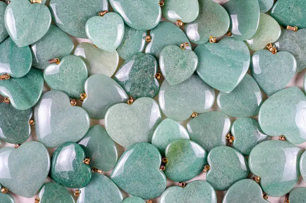 Many heart-shaped semi-precious stones of  green aventurine as background