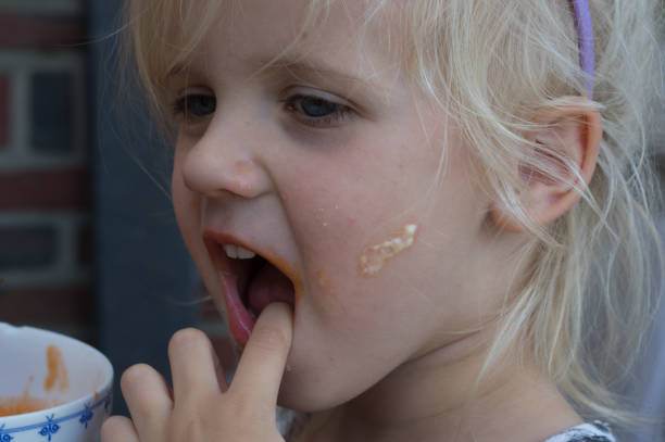 Cute little blond longhair girl is eating a sandwich outdoors. Family picnic recreational activity outdoors.