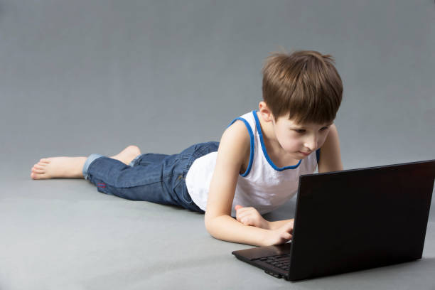istock Child with a computer. The boy is lying on the floor with a laptop 1166865264