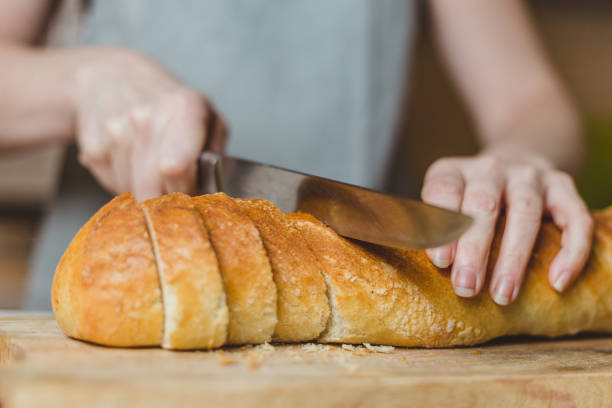 istock Fresh Crisp White Wheat Bread - Female Hands Slicing Baguette 1166865605