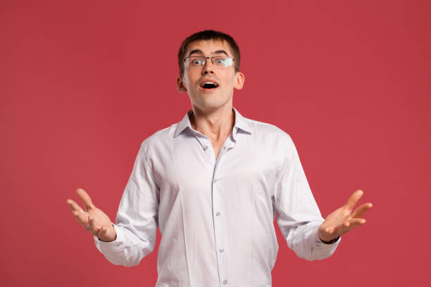 istock Young man in a classic white shirt is posing over a pink background 1166865647