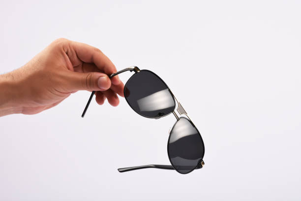 istock Male hand holding sunglasses on white background 1166866418