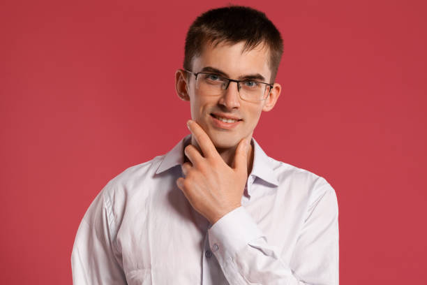 istock Young man in a classic white shirt is posing over a pink background 1166866566