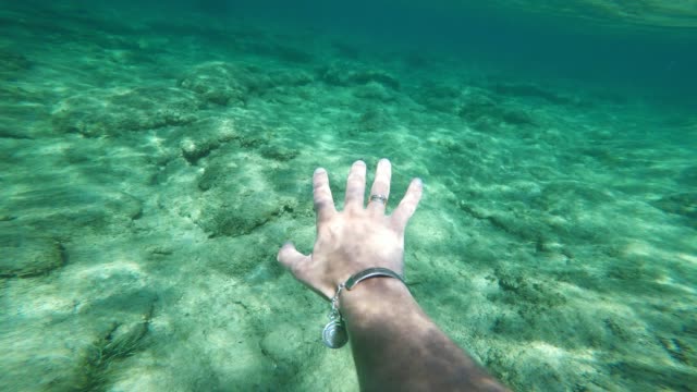 reaching human hand underwater, white skin, sunbeams, sun rays