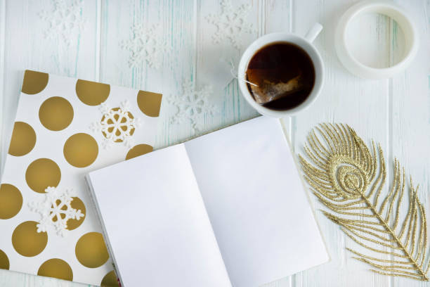 istock Sample layout of New Year's greetings with snowflakes, open notebook, cup of tea on a light wooden background. Frame for text greetings for Christmas. Blog post publication, email newsletter template 1166872792