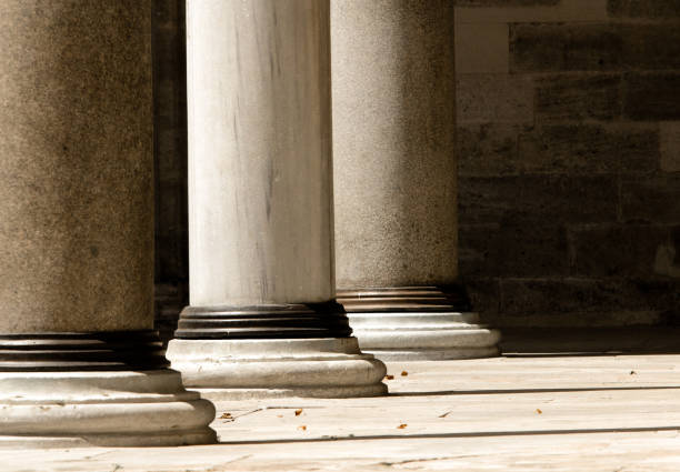 istock Detail of three doric order marble columns with simple bases and bodies under sunlight. 1166873871