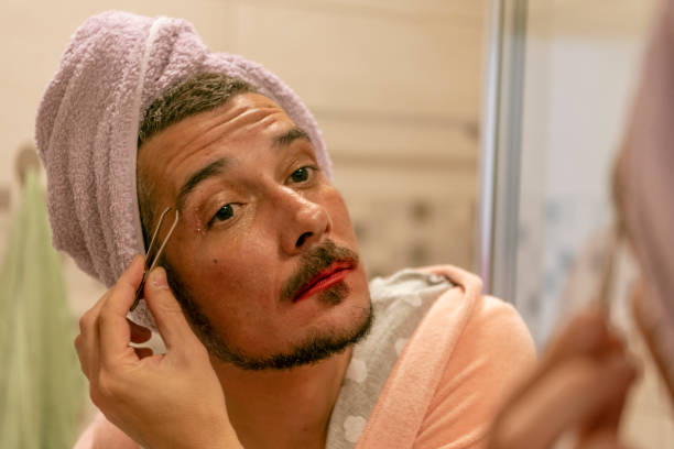 istock Bisexual Person is Plucking Eyebrows in Front of Mirror at Home. 1166874774