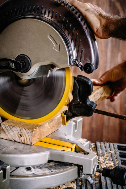 Male Hispanic carpenter using bevel compound miter saw at home workshop Male Hispanic carpenter using bevel compound miter saw at home workshop miter saw stock pictures, royalty-free photos & images