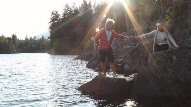 istock Couple help each other down to lakeshore at sunrise 1166882767
