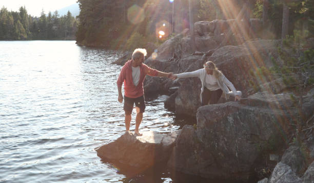 istock Couple help each other down to lakeshore at sunrise 1166882769