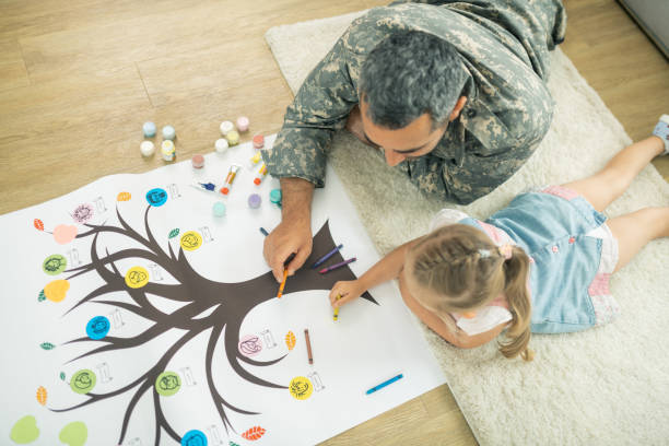 Father and daughter lying on the floor and painting family tree Lying on floor. Top view of caring father and daughter lying on the floor and painting family tree family trees stock pictures, royalty-free photos & images