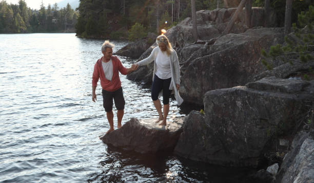 istock Couple help each other down to lakeshore at sunrise 1166882834