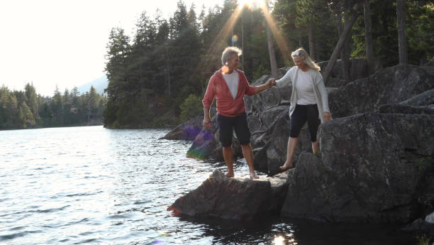 istock Couple help each other down to lakeshore at sunrise 1166882835