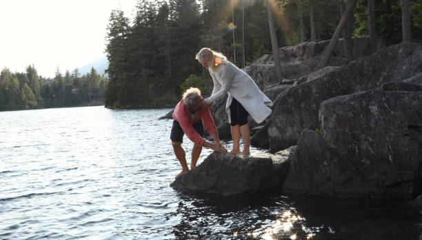 istock Couple help each other down to lakeshore at sunrise 1166882875