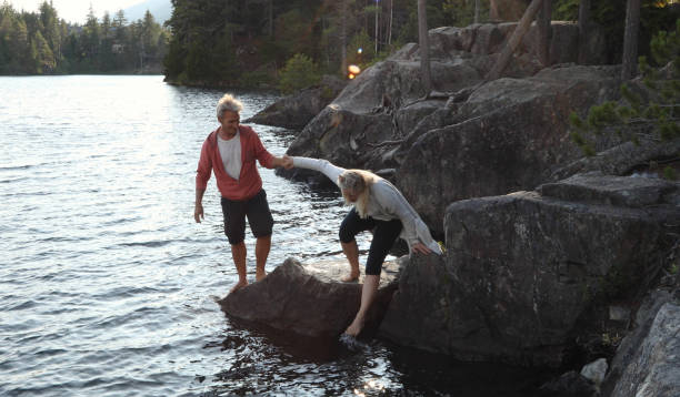 istock Couple help each other down to lakeshore at sunrise 1166882916