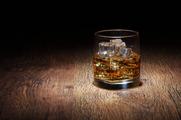 Scotch in glass tumbler with ice rocks on old wood surface A Scotch in glass tumbler with ice rocks on old wood surface amber black photography stock pictures, royalty-free photos & images