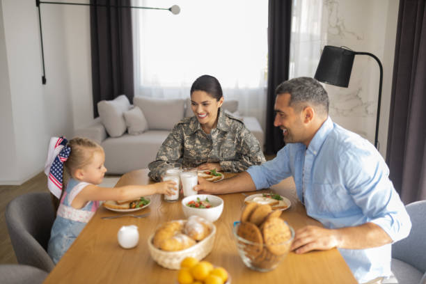 istock Military woman smiling broadly while having breakfast with family 1166883731