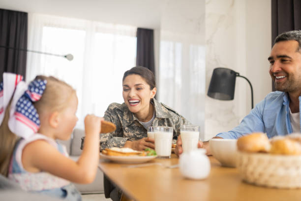 istock Military woman laughing while looking at her daughter eating cookie 1166883732