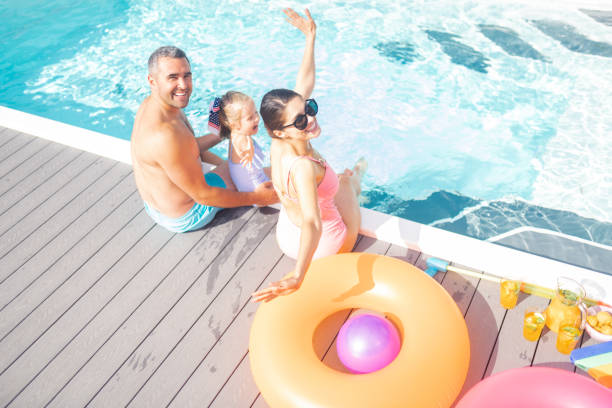 istock Parents and daughter feeling cheerful resting near pool 1166883818