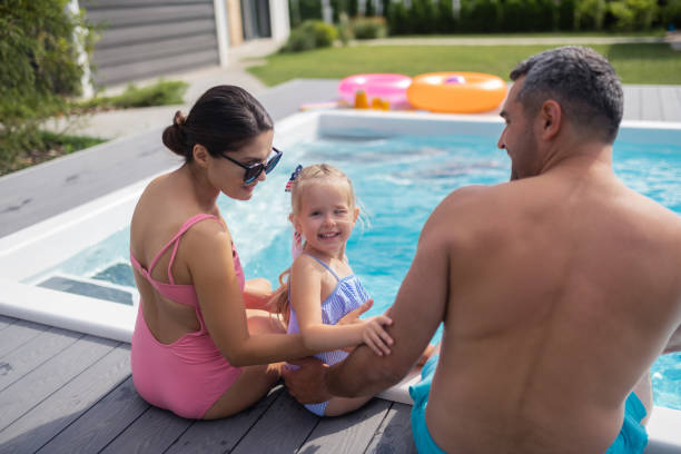 istock Daughter smiling while resting near pool with mom and dad 1166883891