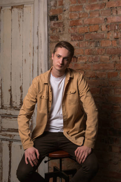 istock Sad and thoughtful young guy sitting on a chair in loft Studio. 1166886773
