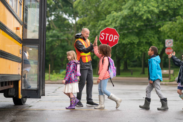szczęśliwy strażnik przejścia daje dzieciom piątki, gdy wsiadają do autobusu szkolnego - school bus education transportation school zdjęcia i obrazy z banku zdjęć